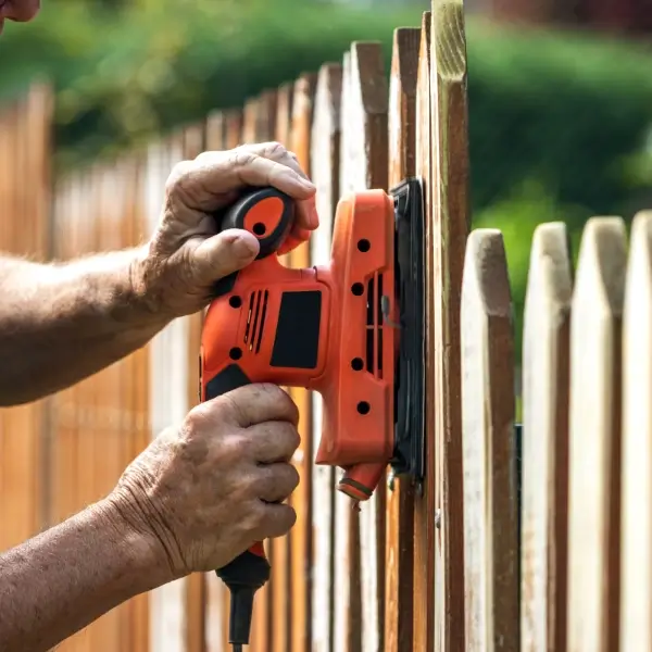 Zaunbau: Handwerker mit Schleifgerät